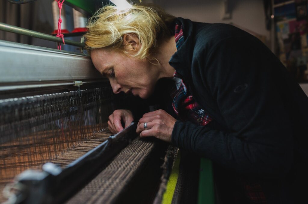 Weaver inspecting tweed on an industrial loom
