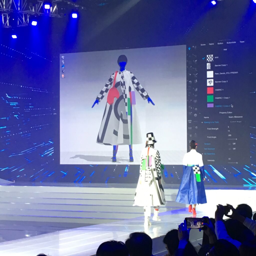 Runway show with a digital garment projected on screen behind the models